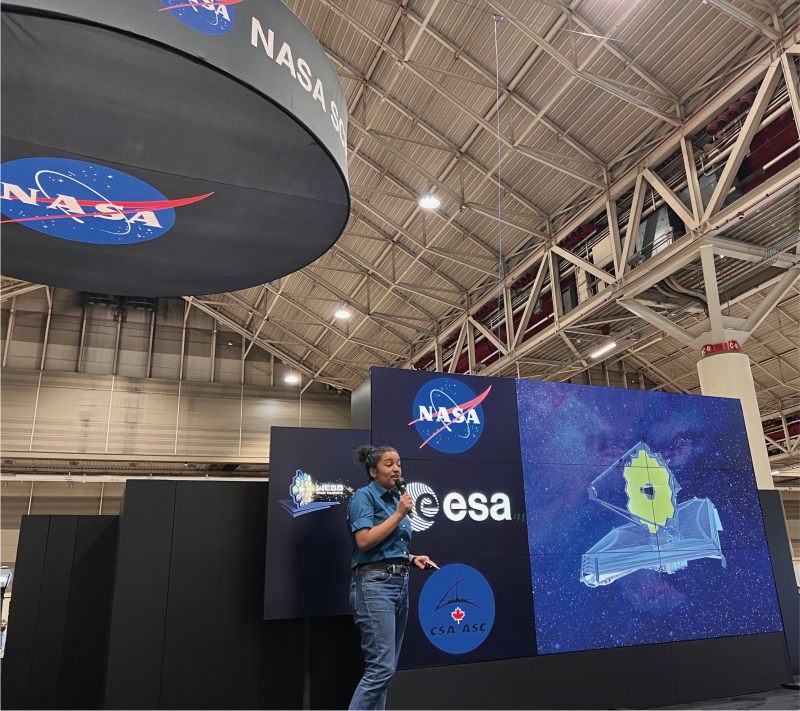NASA researcher for JWST speaking at a NASA event in front of a screen with the JWST.