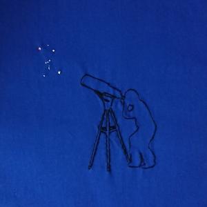 The outline of a person observing Orion through a telescope embroidered with black thread. The constellation of Orion is embroidered in white thread.