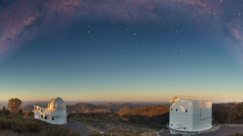 Photograph of two telescope domes, with the Milky Way observed overhead