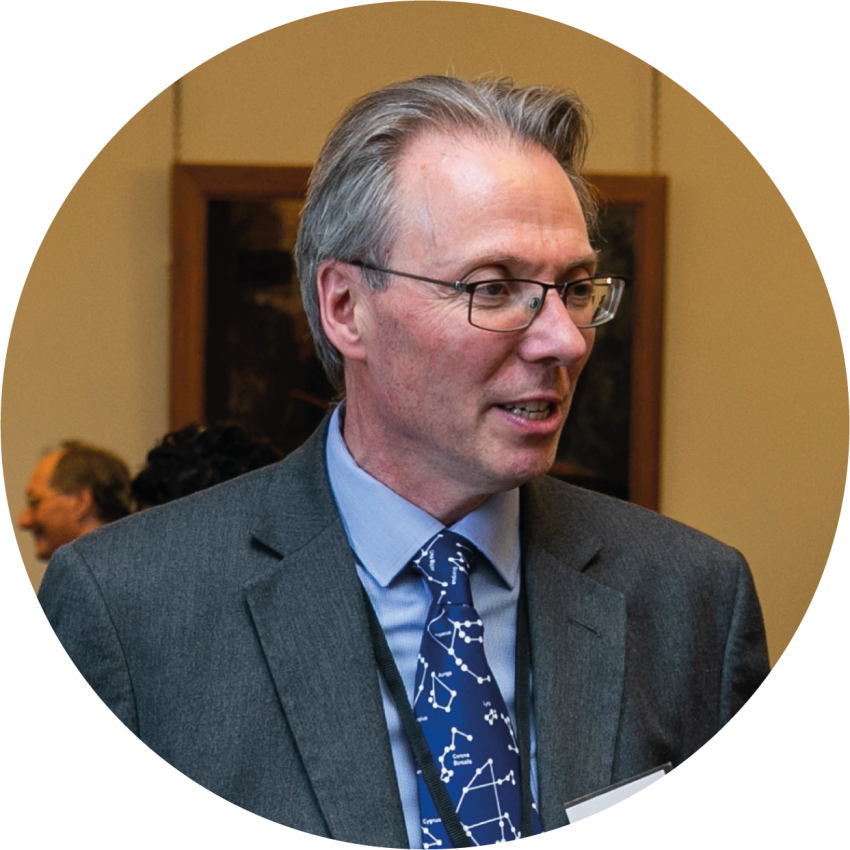 Prof Kevin Walsh in an astronomy tie and glasses speaking at Parliament. 