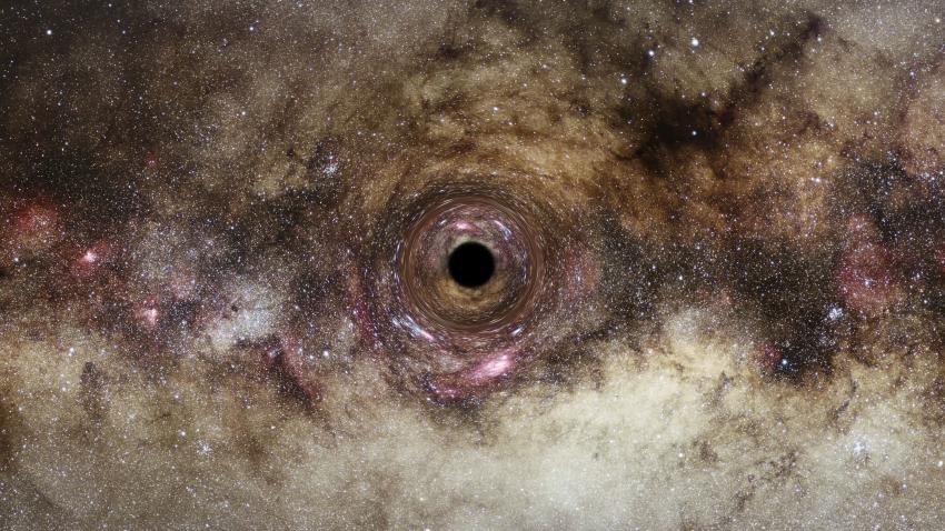 An image of the Milky Way warped around a small black circle at the centre of the image.