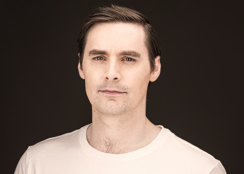 Headshot of a man wearing a white t-shirt. 