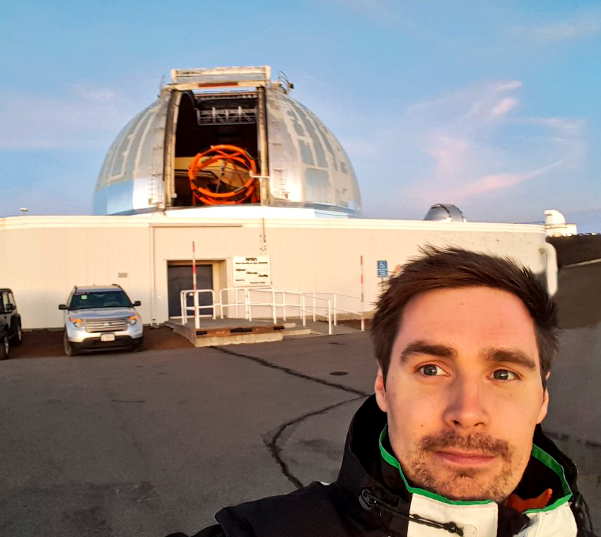A large Earth-based telescope in the background with an astronomer taking a selfie.