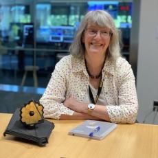 Professor Gillian Wright sitting at a table with a model of JWST