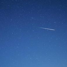 An image of a blue night sky with a single meteor visible in the centre of the frame.