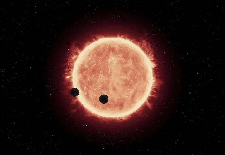 This artist's impression shows two Earth-sized worlds passing in front of their parent red dwarf star in the TRAPPIST-1 system 40 light-years away.