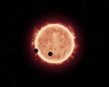 This artist's impression shows two Earth-sized worlds passing in front of their parent red dwarf star in the TRAPPIST-1 system 40 light-years away.